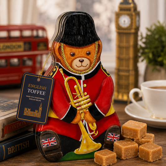Decorative bear figurine in a British uniform with a trumpet, surrounded by English toffee and a cup of tea, with Big Ben in the background.