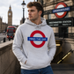 Person wearing a hoodie with a 'Mind the Gap' design in front of Westminster Station.