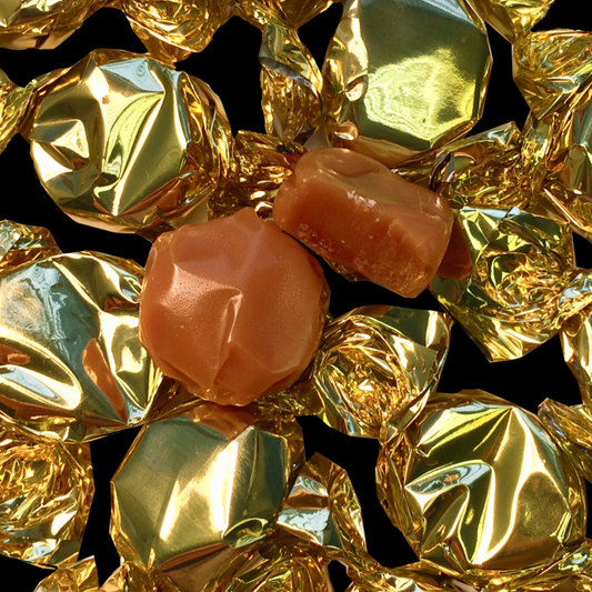 Close-up of gold-wrapped candies with a few pink ones on a black background