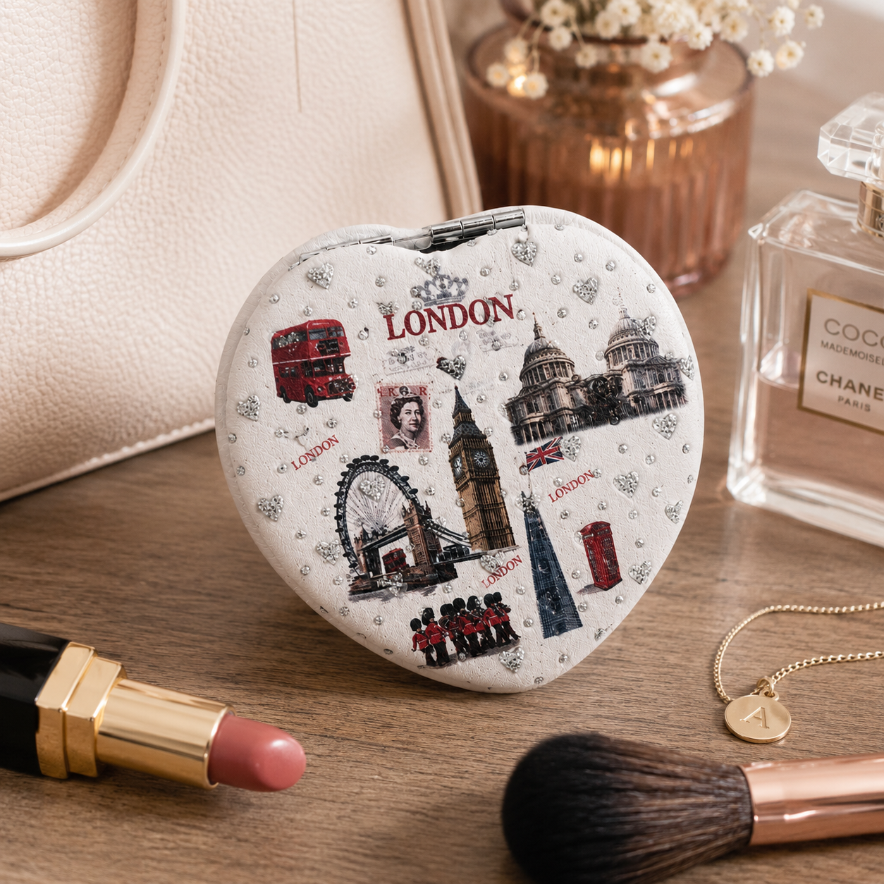 Heart-shaped compact mirror with London-themed design on a wooden surface with makeup items.