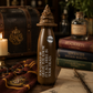 Brown bottle with text in a magical-themed setting with books and a candle.