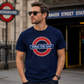 Man wearing a navy blue t-shirt with a 'Mind the Gap' design in front of Baker Street Station.