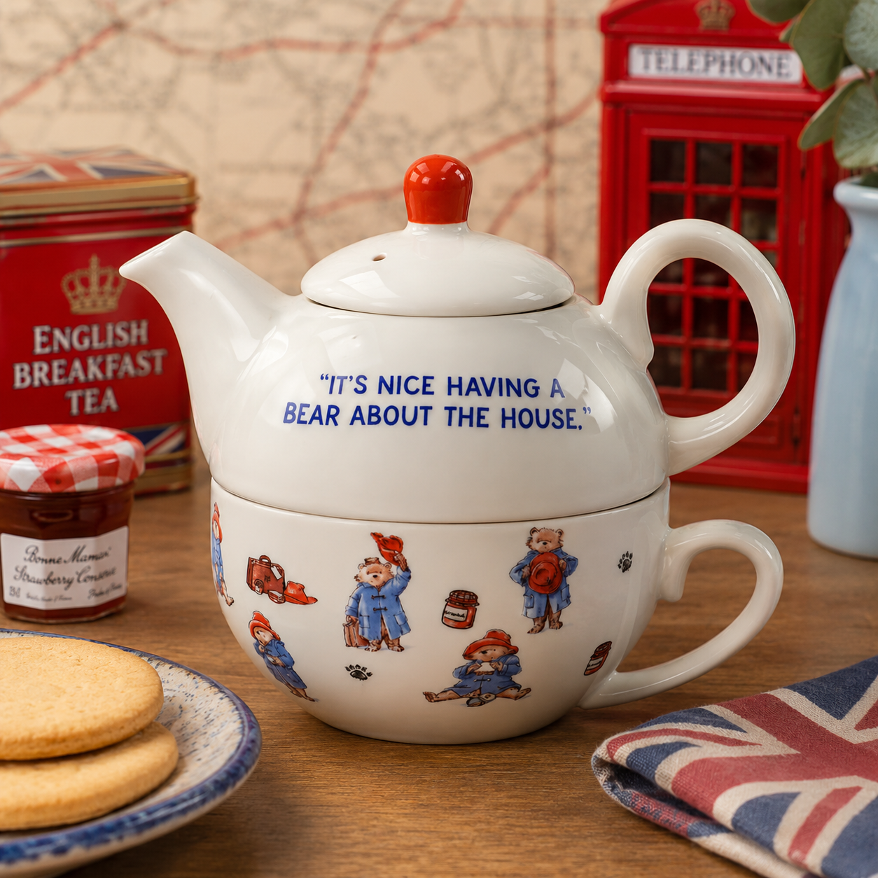 Official Paddington Bear Tea-for-One teapot and cup set styled in a traditional British afternoon tea scene with Union Jack accents and classic tea-time accessories.