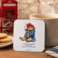 Official Paddington Bear coaster displayed beside a mug of tea and biscuits in a cosy British-inspired tea setting with classic London décor.