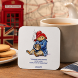 Official Paddington Bear coaster displayed beside a mug of tea and biscuits in a cosy British-inspired tea setting with classic London décor.