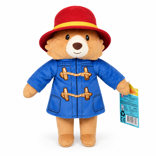 Official Paddington Bear plush toy wearing a blue duffle coat and red hat on a white background with soft studio shadow.