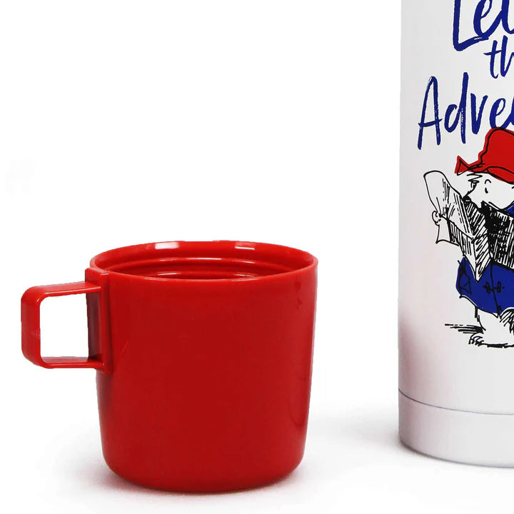 Red mug next to a white box with a character illustration and text on a white background