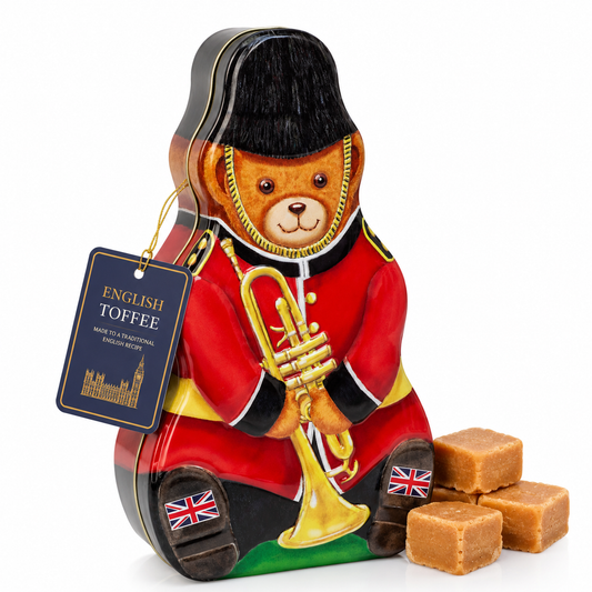 Teddy bear-shaped English toffee tin with a tag and toffee pieces on a white background