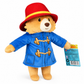 Three-quarter view of the Official Paddington Bear plush featuring his signature blue duffle coat, red hat and official swing tag on a white background.