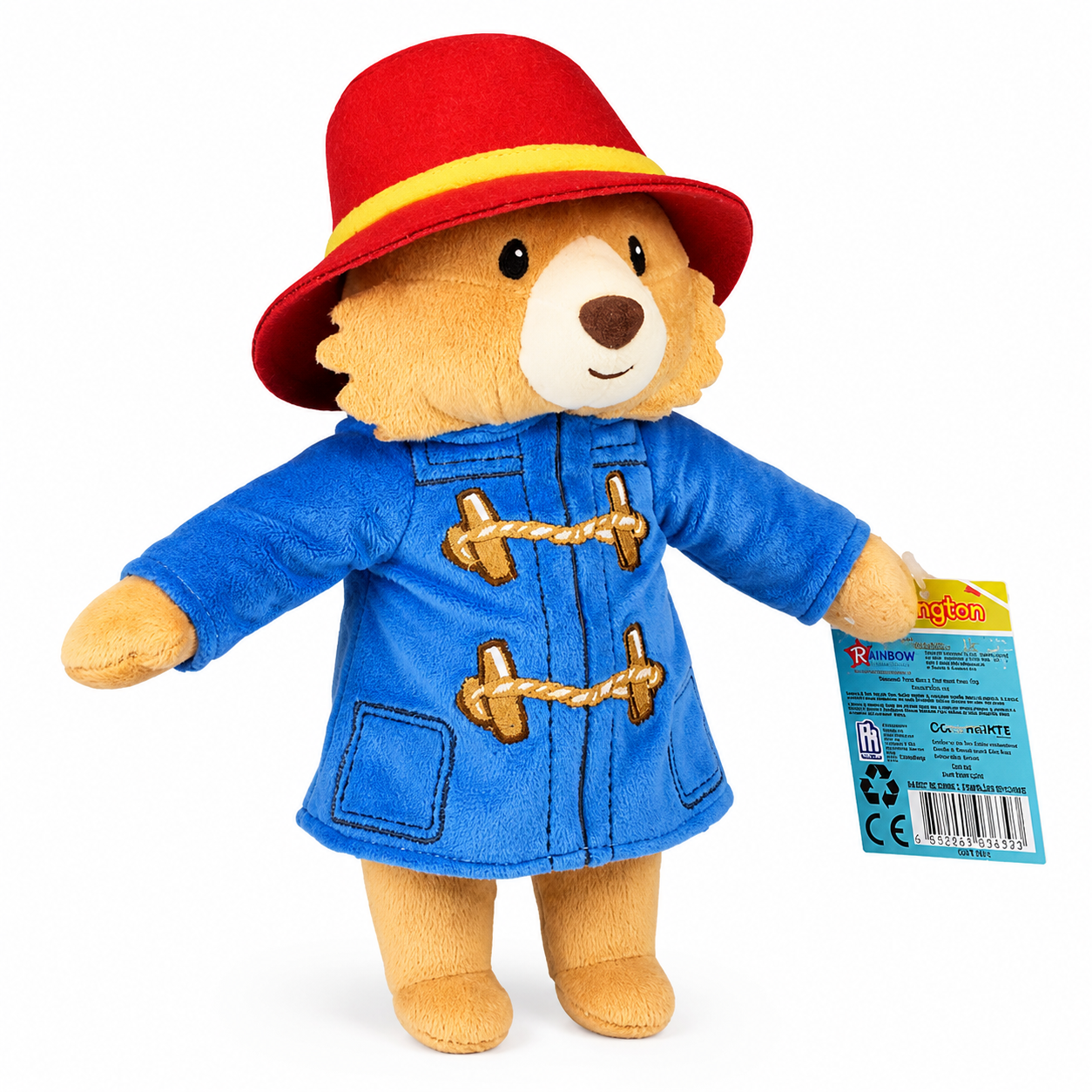 Three-quarter view of the Official Paddington Bear plush featuring his signature blue duffle coat, red hat and official swing tag on a white background.