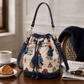 Paddington Bear print bucket bag displayed on a café table beside a croissant, coffee, newspaper and sunglasses.